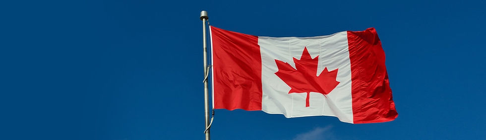A Canada flag with a blue sky in the background.