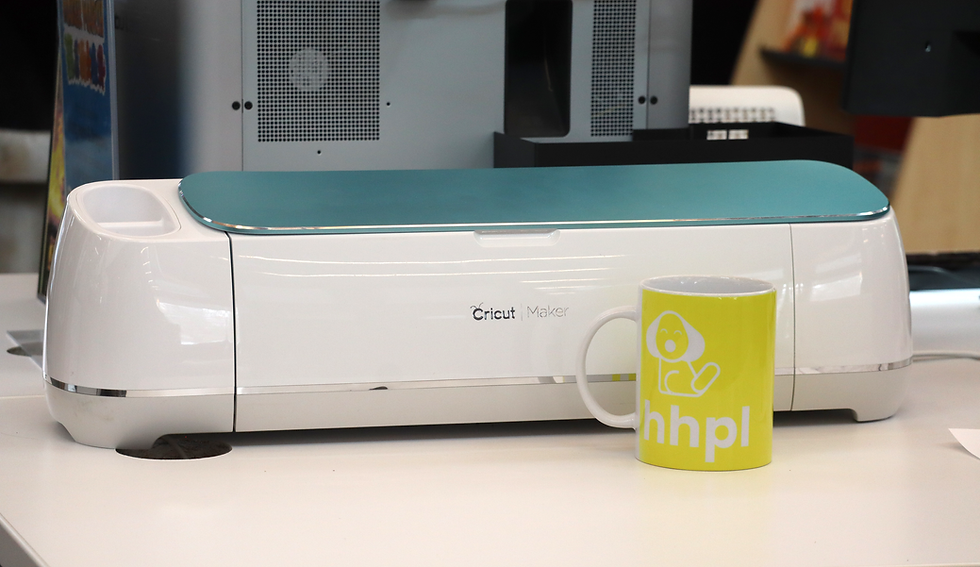 A cricut machine on a desk with a mug in front of it.