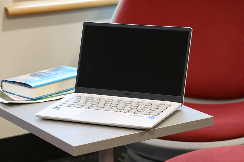 A laptop sitting on a small table with books in the background.
