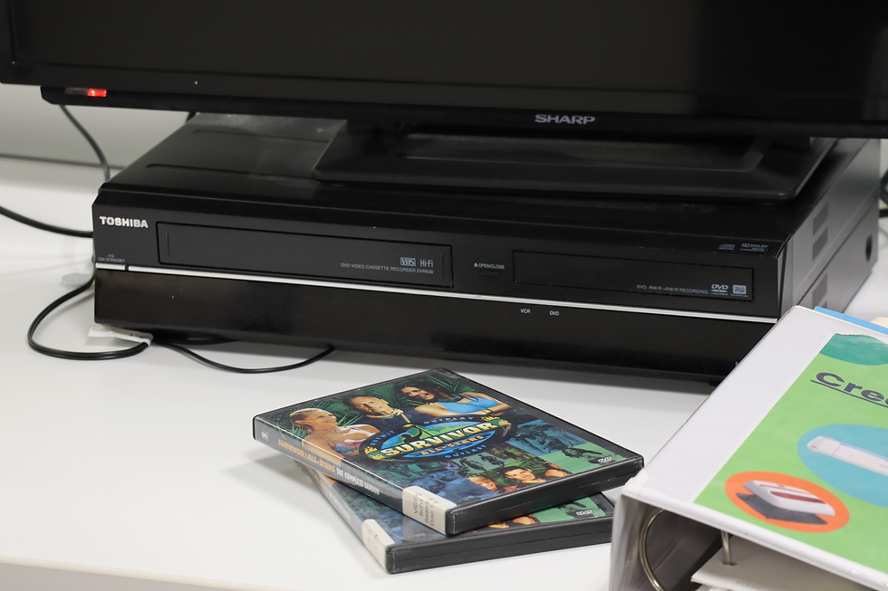 A VHS player on a desk with a TV on top, and two DVDs in front of it.