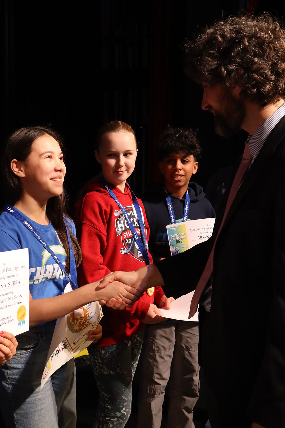 A man shaking hands with a girl during an award ceremony.