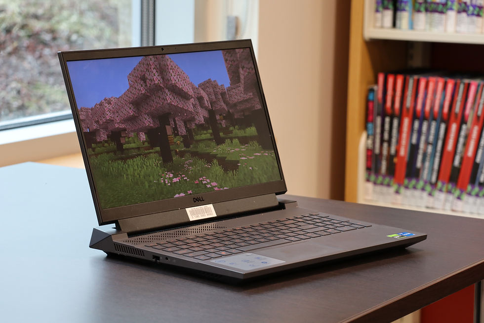 A gaming laptop on a table with books in the background.