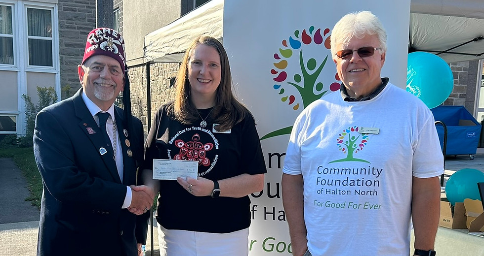 Man in fez presents check to woman at outdoor event