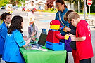 Staff and children with a LEGO figure at an event booth