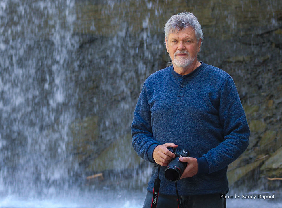 Mark Zelinski, with a camera standing in front of a waterfall