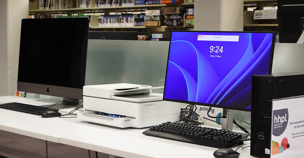 Two computers sitting on a desk with a printer in the middle.