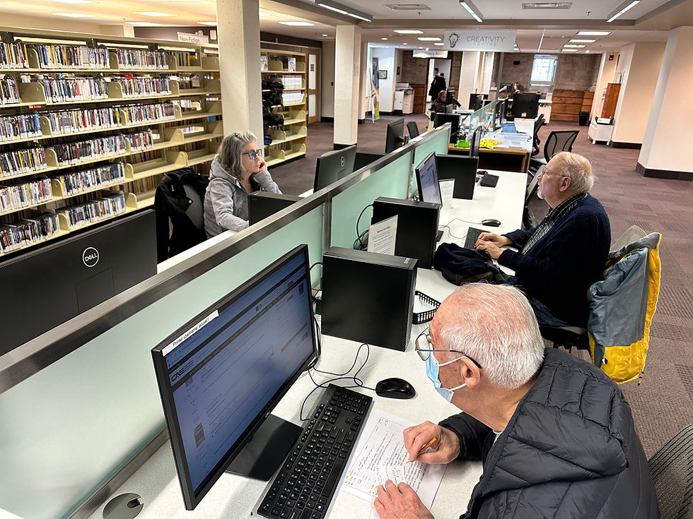A row of computer desk stations with three patrons sitting at their own computer.