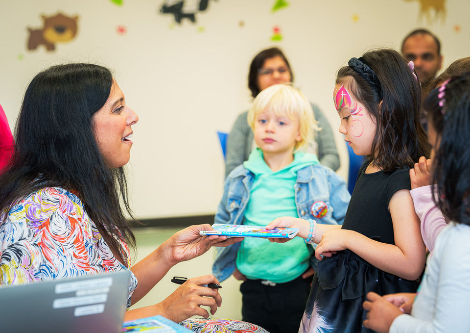 Author handing book to children
