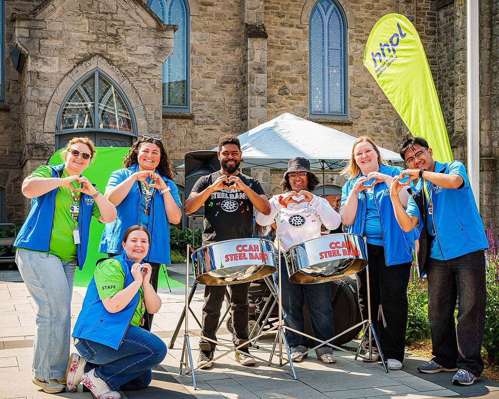 Group of people smiling outdoors with steel drums, making heart shapes with their hands.