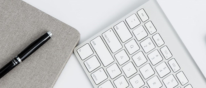 Notebook, pen, keyboard, and smartphone on a desk
