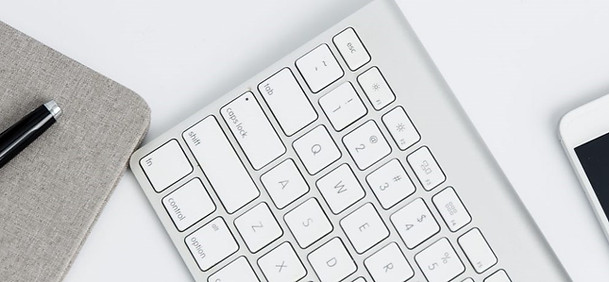 A computer case, pen, keyboard and smartphone on a white background.