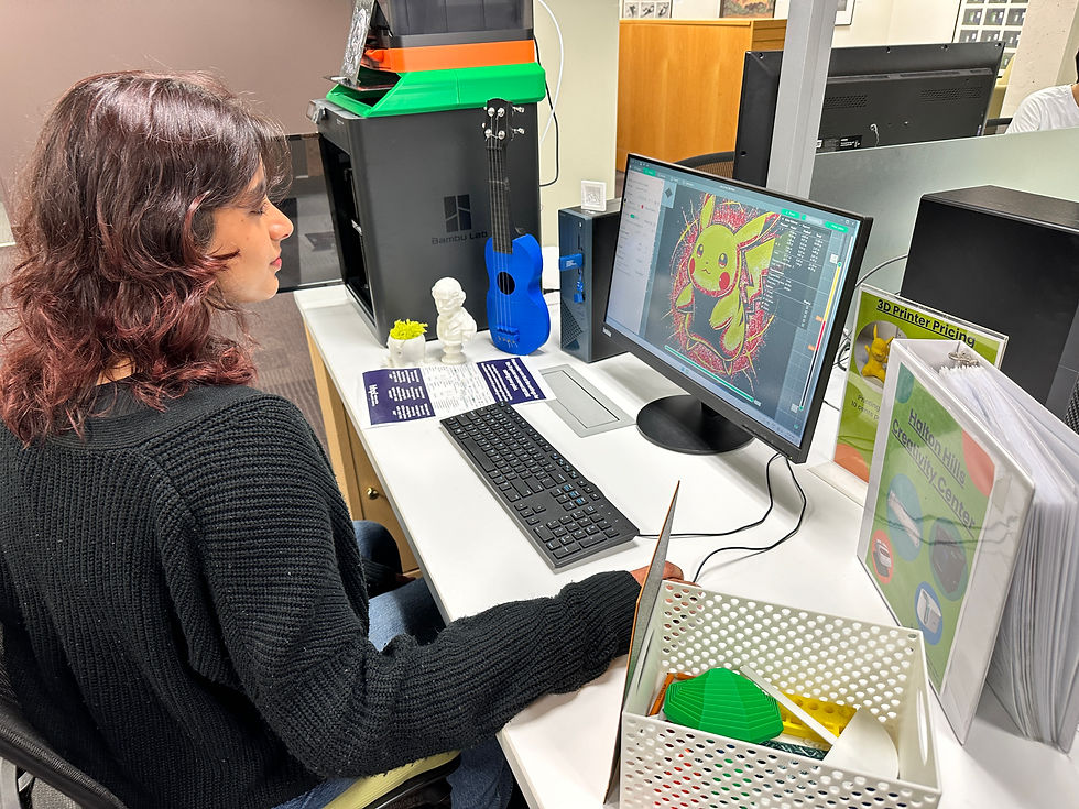Person using a computer to design a 3D model next to a 3D printer in a library makerspace.