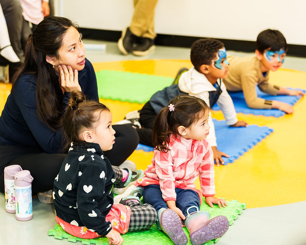 Adult and young children engaged in an activity on colorful mats