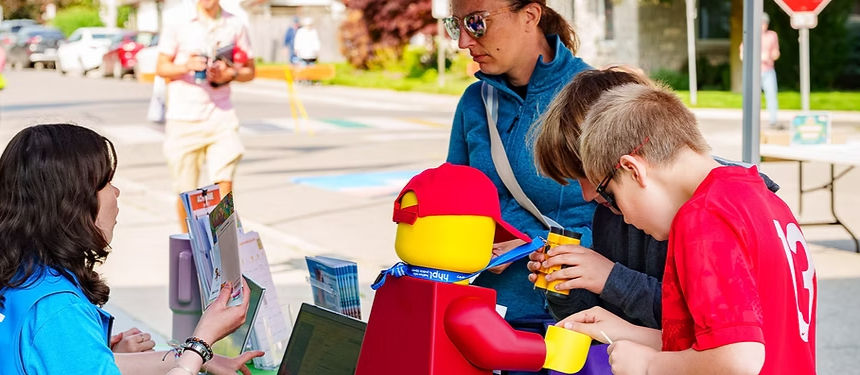 Adults, children, and a large Lego figure at a community event