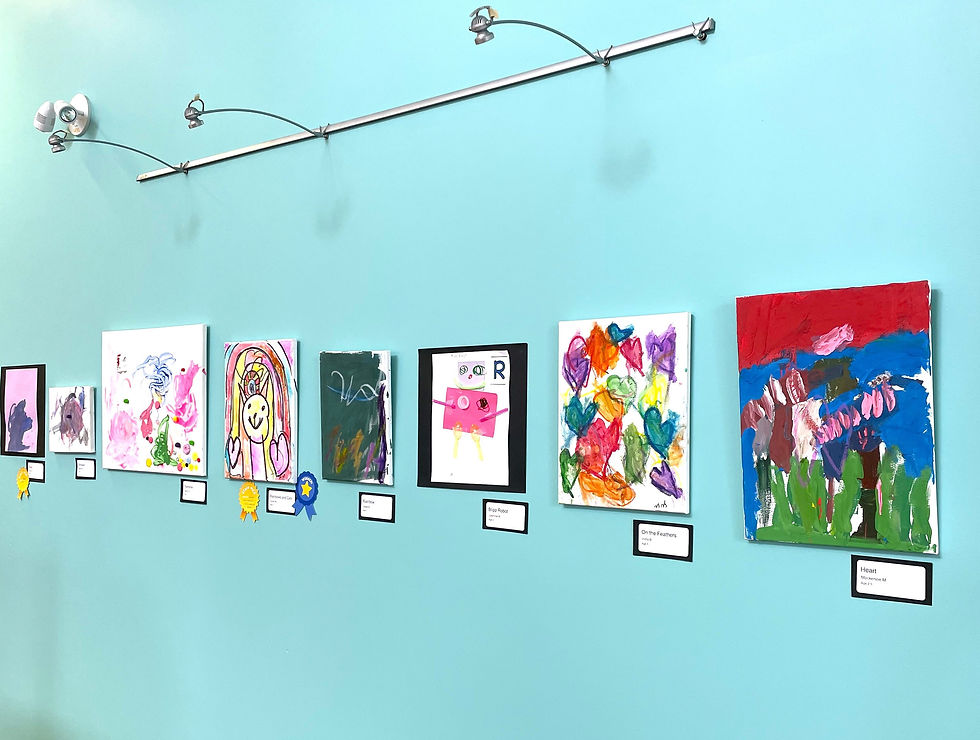 A display of children's colorful paintings hanging on a light blue wall.