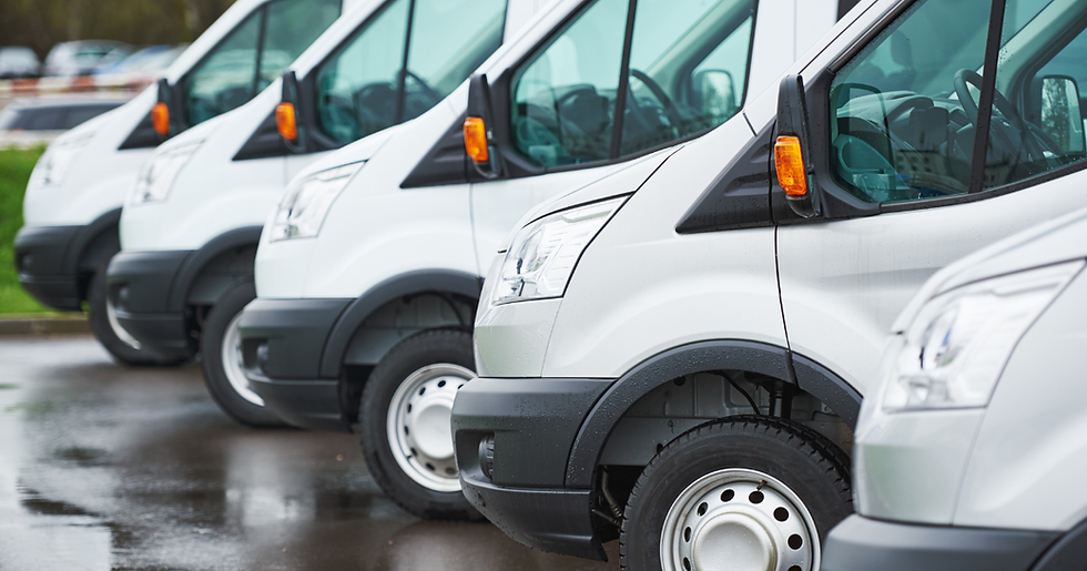 A row of white delivery vans parked side by side in a lot.